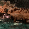 Explora "Descubre la Cova de S’Aigua en Menorca", donde delicadas estalactitas cuelgan sobre una piscina turquesa, reflejando bellamente las fascinantes formaciones rocosas. - ForTwo - Planes para parejas
