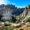 Experimente "Descubre la Historia y Naturaleza de Antequera", donde paisajes rocosos con formaciones altas y estratificadas se fusionan con una exuberante vegetación bajo un cielo azul brillante, combinando naturaleza e historia sin esfuerzo. - ForTwo - Planes para parejas