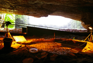 El sitio arqueológico de excavación en la cueva refleja la Neocueva de Altamira, con herramientas y luces alrededor de un pozo, invitando a "Descubrir la Neocueva de Altamira" y destapar los misterios enterrados en las profundidades de la historia. - ForTwo - Planes para parejas