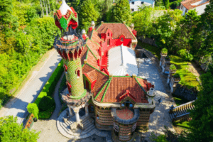 Una vista aérea del vibrante Capricho de Gaudí, que recuerda el estilo caprichoso de Gaudí, revela sus coloridos azulejos rodeados de exuberante vegetación. - ForTwo - Planes para parejas