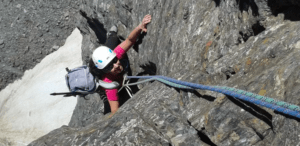 Una persona atrevida participa en la Escalada en Roca para Parejas Aventureras, escalando un acantilado empinado con casco y mochila, utilizando hábilmente cuerdas para la seguridad, ideal para parejas aventureras que buscan emoción y desafío al aire libre. - ForTwo - Planes para parejas