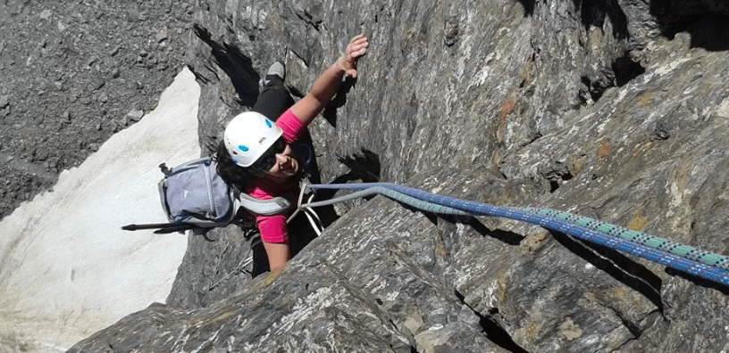 Una persona atrevida participa en la Escalada en Roca para Parejas Aventureras, escalando un acantilado empinado con casco y mochila, utilizando hábilmente cuerdas para la seguridad, ideal para parejas aventureras que buscan emoción y desafío al aire libre. - ForTwo - Planes para parejas