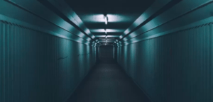 El túnel angosto y poco iluminado de Mérida, con paredes corrugadas y luces fluorescentes en el techo, recuerda a una escena de Escape Room en Mérida, mientras se aleja siniestramente hacia la oscuridad. - ForTwo - Planes para parejas
