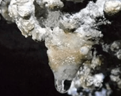 Un primer plano de una pequeña estalactita con gotas de agua en el oscuro entorno de la Cueva del Seso, una joya escondida para los amantes de la espeleología, cerca de Boltaña. - ForTwo - Planes para parejas