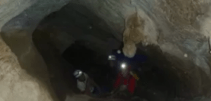 Dos aventureros con casco, con luces iluminando su camino, exploran un oscuro túnel de cueva, encarnando el espíritu de "Espeleología en la Sierra de las Nieves". - ForTwo - Planes para parejas