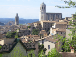 Disfrute de un panorama memorable de Gerona, con tejados de terracota, una gran catedral y una exuberante vegetación bajo un cielo azul en la Excursión a Gerona y Figueres. - ForTwo - Planes para parejas