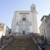 Una amplia escalera de piedra conduce a un imponente edificio histórico blanco con detalles ornamentales y una ventana redonda. Explora el encanto de Girona y su impresionante arquitectura con nuestra aventura "Explora Girona en 48 Horas". - ForTwo - Planes para parejas