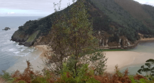 Un paisaje costero con playas de arena, olas, acantilados boscosos y un cielo nublado invita a la aventura. Cerca de allí, "Explora la Cueva del Soplao" invita a los amantes de la exploración. - ForTwo - Planes para parejas