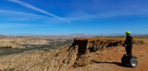 En Segway, una persona explora el vasto desierto bajo un cielo azul infinito. La agreste belleza de la Sierra de Castril invita a los aventureros a descubrir sus maravillas ocultas con la experiencia "Explora la Sierra de Castril en Segway". - ForTwo - Planes para parejas