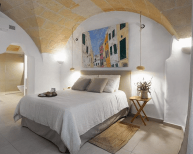La acogedora habitación del Hotel Nou Sant Antoni: En el Corazón de Ciutadella cuenta con un techo abovedado, decoración neutra, arte mural y una iluminación tenue que da acceso al baño. Ideal para su estancia en el corazón de Ciutadella. - ForTwo - Planes para parejas
