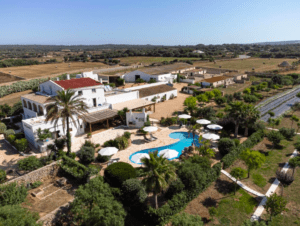 Vista aérea de una finca rural que parece un lujoso Hotel Rural en Menorca, resaltada por una piscina en medio de exuberantes campos y vegetación. - ForTwo - Planes para parejas