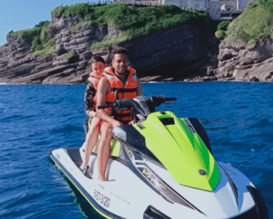 Dos amantes de las emociones fuertes con chalecos salvavidas disfrutan de un paseo en moto acuática por la Costa de Cantabria, deslizándose por aguas azules cristalinas cerca de impresionantes acantilados rocosos. - ForTwo - Planes para parejas