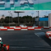 Alguien está corriendo en una emocionante pista con barreras rojas y blancas y una gran pancarta en lo alto, sintiendo la emoción del Kart Extreme en Málaga. - ForTwo - Planes para parejas