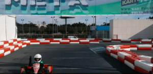 Alguien está corriendo en una emocionante pista con barreras rojas y blancas y una gran pancarta en lo alto, sintiendo la emoción del Kart Extreme en Málaga. - ForTwo - Planes para parejas