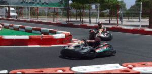 Dos personas experimentan la emoción del Kart Extreme en Málaga, serpenteando entre barreras naranjas y blancas en una pista al aire libre. - ForTwo - Planes para parejas