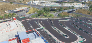 Una vista aérea de Karting en Estepona revela la pista serpenteando elegantemente a través de una exuberante vegetación y carreteras que se cruzan, con un complejo de edificios cercano que realza la pintoresca escena. - ForTwo - Planes para parejas