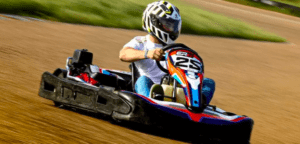 Compitiendo en un kart en la pista de Talavera La Real, esta persona, vestida con ropa informal y casco, disfruta de la emoción del Karting. - ForTwo - Planes para parejas