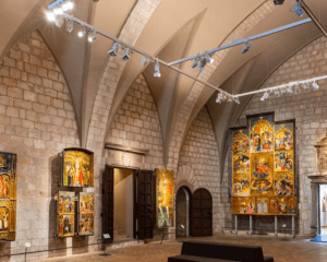 El Museo de Arte de Girona cuenta con una pinacoteca con techos abovedados de piedra, donde se exponen pinturas religiosas y retablos iluminados con focos. - ForTwo - Planes para parejas