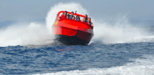 El Paseo de Acrobacias en el Agua en Girona cuenta con una lancha roja cuyos pasajeros realizan emocionantes acrobacias y crean salpicaduras mientras avanzan a toda velocidad por el océano. - ForTwo - Planes para parejas