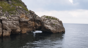 Los acantilados rocosos dominan un mar en calma bajo un cielo nublado cerca de la impresionante zona del Paseo en Barco por la Bahía de Santander. - ForTwo - Planes para parejas