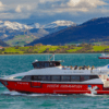 El Paseo en Barco por la Bahía de Santander, una embarcación roja y blanca llamada Visión Submarina, navega por las aguas enmarcadas por montañas nevadas y exuberantes colinas verdes. - ForTwo - Planes para parejas