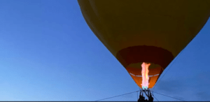 Un globo aerostático se eleva en un cielo azul claro sobre Almodóvar del Río, con una llama brillante calentando el aire en el interior para un inolvidable Paseo en Globo por Almodóvar del Río. - ForTwo - Planes para parejas