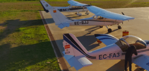 Tres avionetas se encuentran estacionadas en una pista rodeada de césped en Córdoba, y cerca de una de ellas se encuentra un participante de "Piloto por un Día en Córdoba". - ForTwo - Planes para parejas