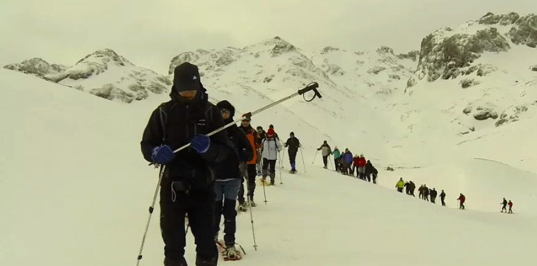 Un grupo explora la impresionante belleza de los Picos de Europa cubiertos de nieve, caminando con raquetas de nieve en línea y vestidos con ropa de invierno utilizando Raquetas de Nieve en Picos de Europa. - ForTwo - Planes para parejas