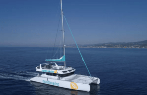 El Recorrido romántico en catamarán, una embarcación blanca con velas turquesas, zarpa por el tranquilo mar azul bajo un cielo despejado. - ForTwo - Planes para parejas