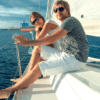 Una pareja disfruta de su recorrido romántico en catamarán, con gafas de sol y con el agua azul clara de fondo. - ForTwo - Planes para parejas