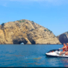 Una emocionante aventura se desarrolla en una Ruta en Moto de Agua por las Islas Medas, mientras dos motociclistas se deslizan por el vibrante océano, con los majestuosos acantilados rocosos de las Islas Medas como telón de fondo impresionante. - ForTwo - Planes para parejas