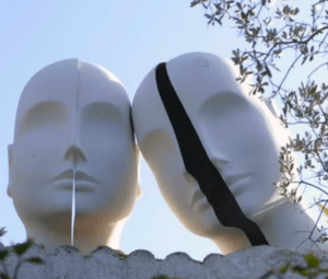 Dos cabezas de maniquí, una adornada con una raya negra, sobre un cielo azul y ramas de árboles, evocan el encanto surrealista de Portlligat. Es como si formaran parte de "Visita la Casa de Dalí en Portlligat", fusionando arte y naturaleza con naturalidad. - ForTwo - Planes para parejas