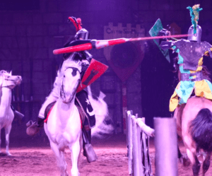 En Tenerife, la Aventura Medieval en Tenerife cautiva al público con caballeros a caballo justando en una animada arena, rodeados de estandartes vibrantes y espectadores cautivados vestidos con trajes medievales. - ForTwo - Planes para parejas