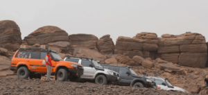 Vehículos todoterreno aparcados sobre terreno rocoso con grandes formaciones rocosas al fondo, encarnando la esencia de una Aventura en 4x4 por Girona. - ForTwo - Planes para parejas
