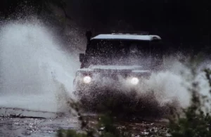 Un todoterreno 4x4 ruge entre el lodo, con sus faros penetrando el caos, rodeado de vegetación difusa. Es una aventura en 4x4 por la Costa del Sol, que evoca terrenos salvajes lejos de sus soleadas costas. - ForTwo - Planes para parejas