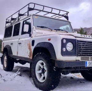 Un 4x4 blanco, parte del paquete "Aventura en 4x4 por la Costa del Sol", está aparcado en un paisaje nevado con baca y laterales embarrados. Su robusta presencia contrasta a la perfección con la tranquilidad de las montañas, evocando la esencia aventurera de la Costa del Sol. - ForTwo - Planes para parejas