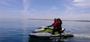 Dos personas con chalecos salvavidas navegan en una Aventura en Moto de Agua en Valencia por las tranquilas aguas bajo un cielo azul con nubes ligeras, abrazando el espíritu de aventura. - ForTwo - Planes para parejas