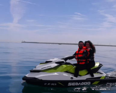 Dos personas con chalecos salvavidas navegan en una Aventura en Moto de Agua en Valencia por las tranquilas aguas bajo un cielo azul con nubes ligeras, abrazando el espíritu de aventura. - ForTwo - Planes para parejas