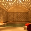 Los Baños Árabes en Menorca ofrecen una lujosa experiencia de spa con una piscina iluminada con velas, un techo ornamentado y toallas rojas y blancas cuidadosamente apiladas que reflejan el encanto de Menorca. - ForTwo - Planes para parejas