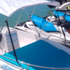 Un barco sin licencia en Alcossebre, con casco blanco, toldo y asientos azules, está atracado junto a motos de agua en las aguas turquesas y disponible para alquilar. - ForTwo - Planes para parejas