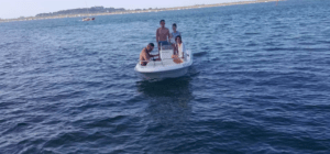 Un grupo de cuatro personas disfruta de un tranquilo paseo por las vastas y tranquilas aguas cercanas a Santander a bordo del Barco sin licencia en Santander, navegando sin esfuerzo mientras la tierra lejana se extiende detrás de ellos. - ForTwo - Planes para parejas