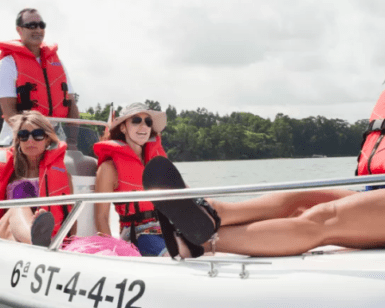 Cuatro personas con chalecos salvavidas navegan pacíficamente en una pequeña embarcación a través de un exuberante lago verde, capturando el encanto de Santander y la libertad de un Barco sin licencia en Santander. - ForTwo - Planes para parejas