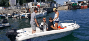 Cuatro personas se deslizan por el agua en un Barco sin licencia en Santander cerca de un muelle, enmarcados por los impresionantes edificios de Santander al fondo. - ForTwo - Planes para parejas