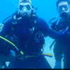 Tres buceadores bajo el agua en Tossa de Mar, con trajes de neopreno y máscaras negras, hacen un gesto a la cámara durante su Bautismo de Buceo en Tossa de Mar. - ForTwo - Planes para parejas