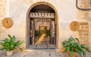 La Cata de Aceite de Oliva y Brunch en Sóller ofrece un entorno sereno con entradas arqueadas rústicas, puertas de madera, plantas verdes en macetas, pisos de piedra y decoración de paredes de mimbre, ideal para brunchs relajados o exquisitas catas de aceite de oliva. - ForTwo - Planes para parejas