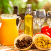 Un brunch vibrante se desarrolla con naranjas, tomates de Sóller, aceitunas, degustación de aceite de oliva y copas de vino dispuestas artísticamente como parte de la experiencia "Cata de Aceite de Oliva y Brunch en Sóller". - ForTwo - Planes para parejas