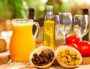 Un brunch vibrante se desarrolla con naranjas, tomates de Sóller, aceitunas, degustación de aceite de oliva y copas de vino dispuestas artísticamente como parte de la experiencia "Cata de Aceite de Oliva y Brunch en Sóller". - ForTwo - Planes para parejas