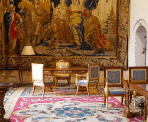 La sala ornamentada, que refleja la grandeza de la Catedral de Mallorca y el Palacio Real, exhibe un tapiz, elegantes sillas, un escritorio de madera y una alfombra colorida dentro de su ambiente histórico. - ForTwo - Planes para parejas