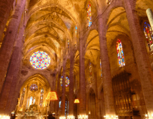 En el interior de la Catedral de Mallorca y Palacio Real, los visitantes quedan cautivados por los altos arcos, los hermosos vitrales y los intrincados detalles del techo que exudan elegancia gótica. - ForTwo - Planes para parejas