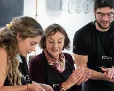 Tres personas con delantales cocinan juntas alegremente, capturando el vibrante espíritu de Valencia mientras disfrutan de una "Clase de cocina española en Valencia: tapas y vinos". - ForTwo - Planes para parejas